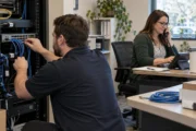 Technician connecting a network switch while an office manager tests a desk phone